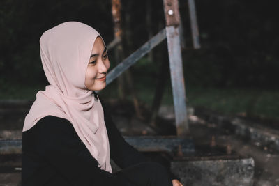 Smiling woman wearing hijab looking away at park