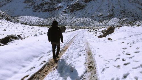 Rear view of man standing on snow covered land