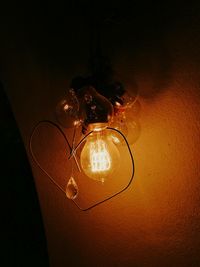 Low angle view of illuminated light bulb against black background