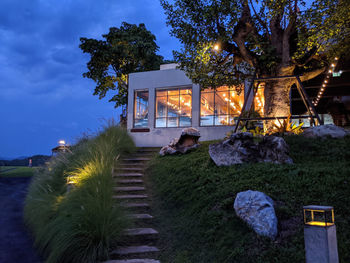 House by trees against sky at night