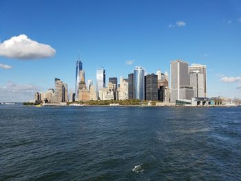 Sea by modern buildings against sky in city