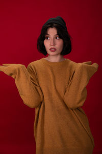 Portrait of young woman standing against red background