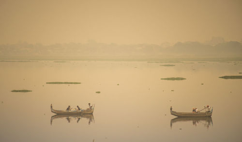 Men fishing in sea against sky