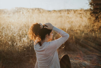 Woman tying hair against plants