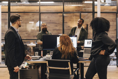 Colleagues and manager discussing over computer in office