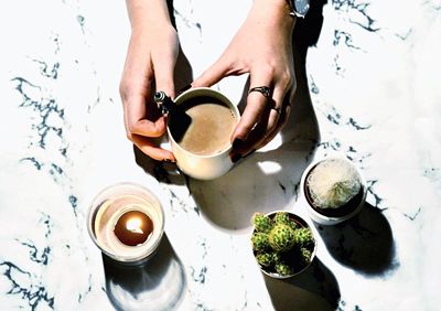 Directly above shot of woman holding coffee mug by tea light candle