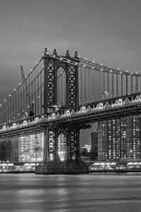 Illuminated bridge over river at night