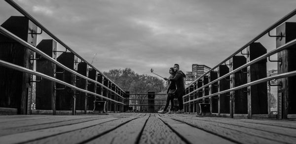 Man walking on bridge in city against sky