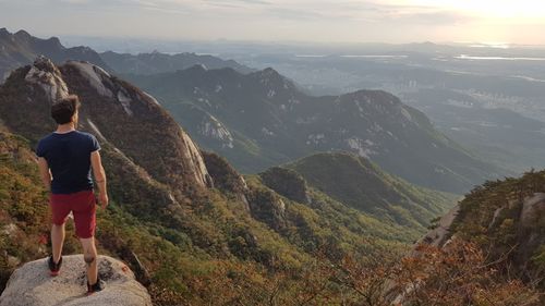 Rear view of woman standing on mountain against sky