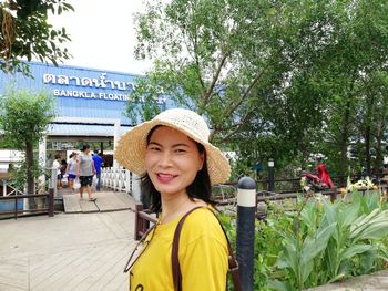 Portrait of smiling woman wearing hat standing in park