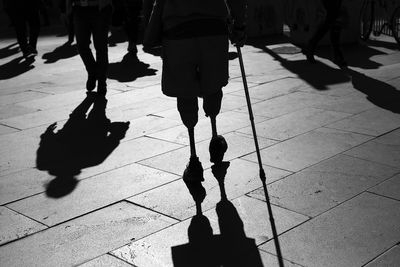 Low section of person with prosthetic legs walking on footpath in city