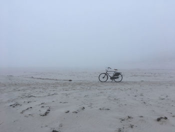 Bicycle on beach against clear sky