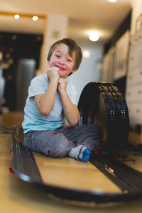 Portrait of boy sitting amidst toy racetrack