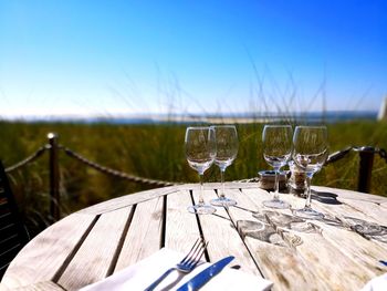 Glasses on table by field against sky