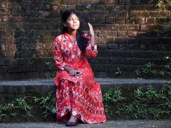 Portrait of young woman standing against wall