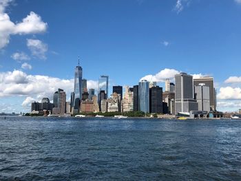 Sea by modern buildings against sky in city