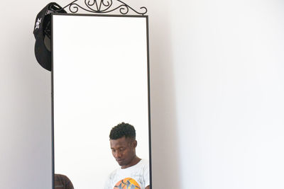 Portrait of young man standing against wall