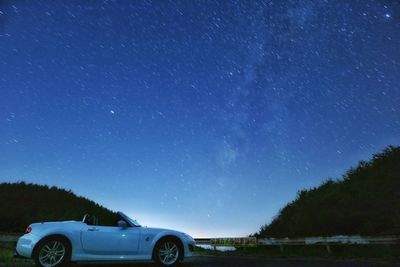 Car on field against sky at night