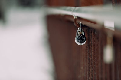 Single combination lock hanging on bridge railing.