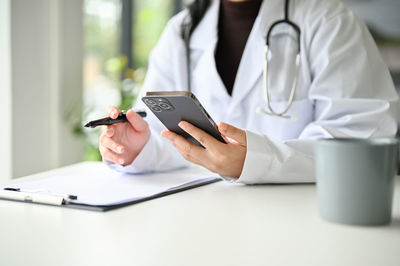 Midsection of doctor using digital tablet