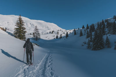 An unrecognizable male hiker wearing snowshoes walking in the french alps