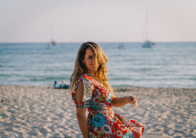 Young woman at beach against sky