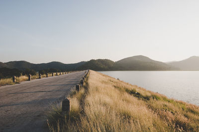 Road leading towards mountains against clear sky