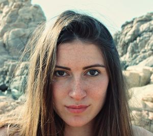 Close-up portrait of beautiful young woman against rock formation