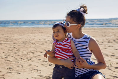 Woman walks with her little son on a sandy beach near the sea in the summer