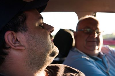 Close-up of man looking at friend sleep in car