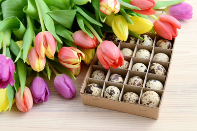 Close-up of tulips and quail eggs in cardboard box on table