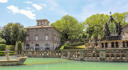 View of building by lake against sky