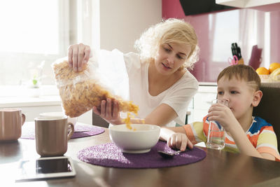 Mother serving breakfast cereal to son at home