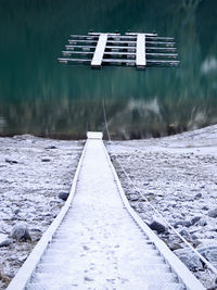 Snow covered railroad tracks by lake during winter