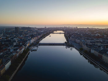 High angle view of river by buildings against sky during sunset