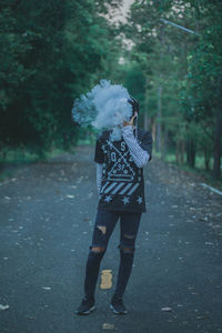 Rear view of woman with umbrella walking on road