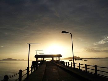 Silhouette pier over sea against sky during sunset