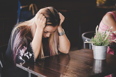 Tensed mid adult woman sitting on table in restaurant