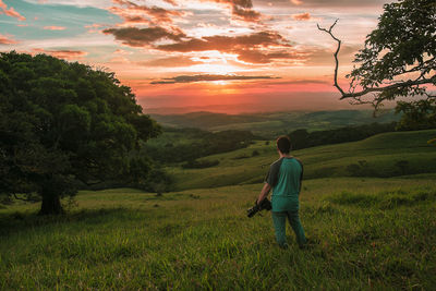 Rear view of man walking on field against sky