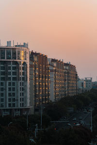 Buildings in city against sky at sunset