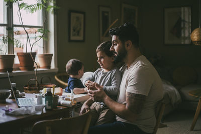 Father with children taking online advice on video with female doctor at home during pandemic