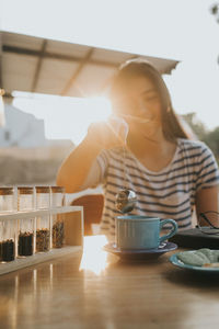 Young woman having tea at cafe during sunset
