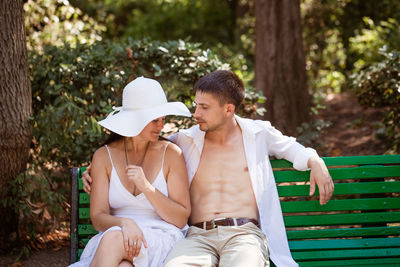 Young couple in love together on a park bench in light clothes on a summer day