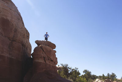 Low angle view of man on rock against sky
