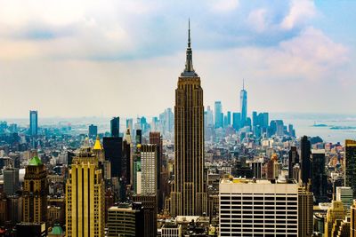 Aerial view of buildings in city against cloudy sky