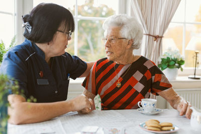 Female caretaker consoling senior woman at nursing home