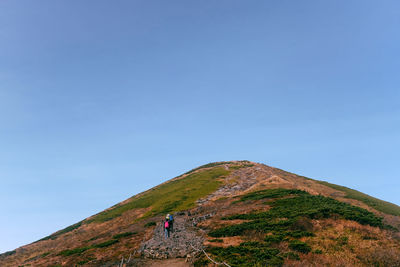 Rear view of people walking on mountain against sky