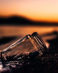 Close-up of jar on shore at beach during sunset