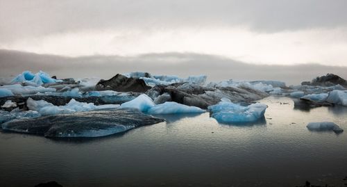 Scenic view of icebergs in sea against sky