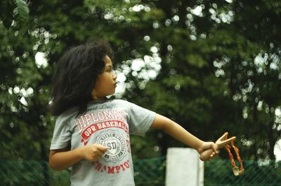 Close-up of young woman standing against trees